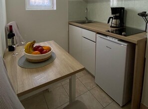 A compact kitchen with a sink, a coffee maker, and a small refrigerator.
