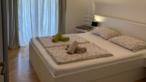 Un lit bien fait, avec une literie à motifs floraux, une lampe de chevet et une chaise.