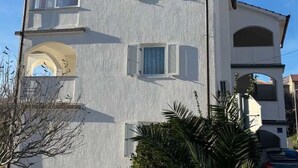 Un bâtiment à deux étages avec des murs extérieurs blancs, de nombreuses fenêtres dotées de volets et une entrée en arc de cercle.