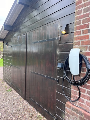 Eine dunkle Holztür zur Garage mit angebauter Tesla-Ladestation an der Wand.