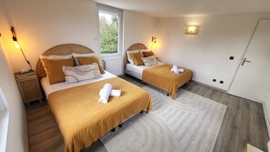 Ein Schlafzimmer mit zwei Betten, einem Fenster, einem Heizkörper, Nachttischlampen und einer Tür.