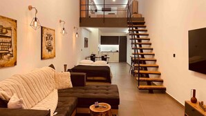 Un salon moderne avec un canapé, une table basse et un escalier menant à un niveau supérieur.