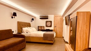 Une chambre à coucher avec un lit, un canapé, une télévision, une horloge et une armoire en bois.