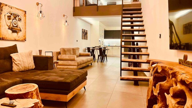 Un salon moderne avec une chambre à l’étage, un coin repas et une cuisine.