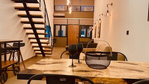 Un espace repas moderne avec une table en bois, des chaises noires et un escalier.
