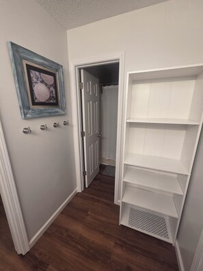 A hallway with a white door, a framed picture on the wall, and a white shelving unit. - Emerald Coast 3-bedroom house in lovely Navarre, 1/2 acre lot, 5 min from Beach (Navarre)