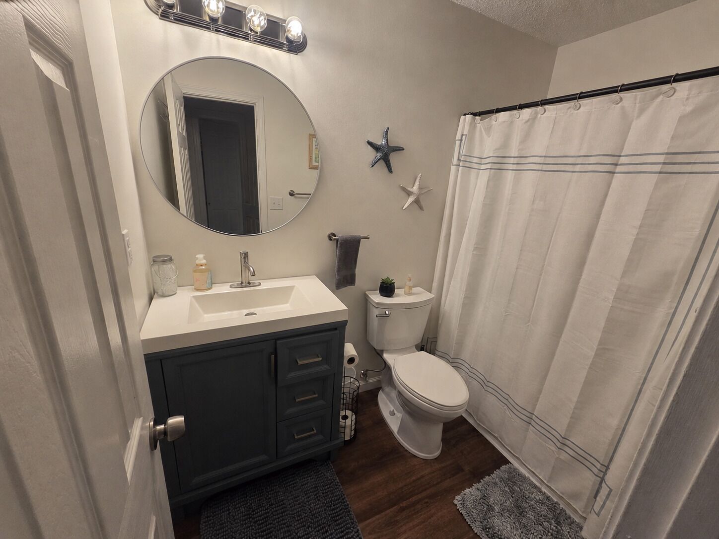 A bathroom with a vanity, sink, mirror, toilet, and shower curtain.