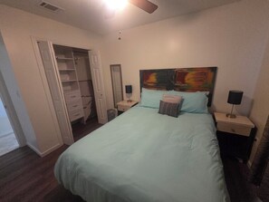 A bedroom with a bed, nightstands, a ceiling fan, a wardrobe, and a mirror. - Emerald Coast 3-bedroom house in lovely Navarre, 1/2 acre lot, 5 min from Beach (Navarre)