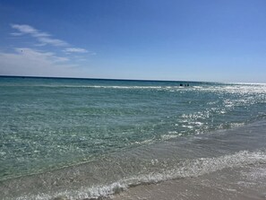 Een strand met helder water, een zandstrand en een verre horizon.