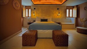 A bedroom with a large bed, two nightstands, a bench, and a ceiling light fixture. - Casa Laja - Hotel Boutique (San Miguel de Allende)