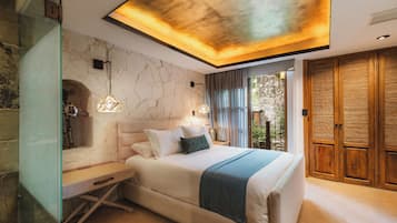 Une chambre moderne avec un mur en pierre, un lit recouvert d’un jeté bleu et une armoire en bois.