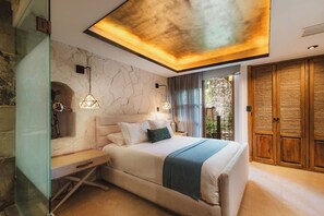 Une chambre moderne avec un mur en pierre, un lit recouvert d’un jeté bleu et une armoire en bois.