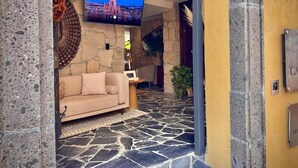 A stone-floored lobby with a sofa and a flat-screen TV mounted on the wall. - Casa Laja - Hotel Boutique (San Miguel de Allende)