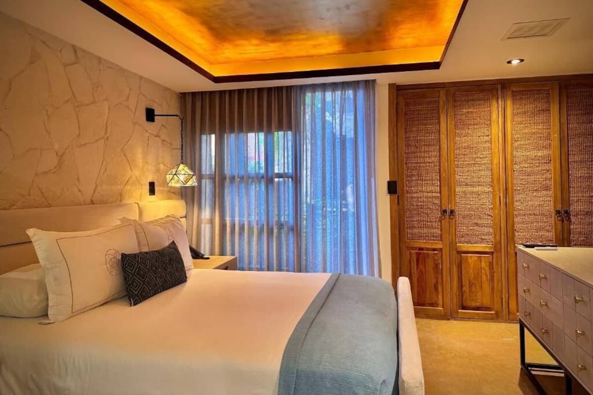 Ein Schlafzimmer mit Bett, Nachttischlampe, Vorhängen, einem Kleiderschrank und einem Schminktisch.