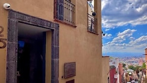 A narrow cobblestone street with a building featuring a stone staircase leading to an entrance. - Casa Laja - Hotel Boutique (San Miguel de Allende)