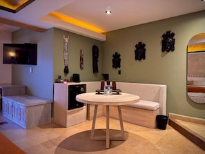 A modern living room with a round wooden table, a sofa, a television, and decorative wall art. - Casa Laja - Hotel Boutique (San Miguel de Allende)