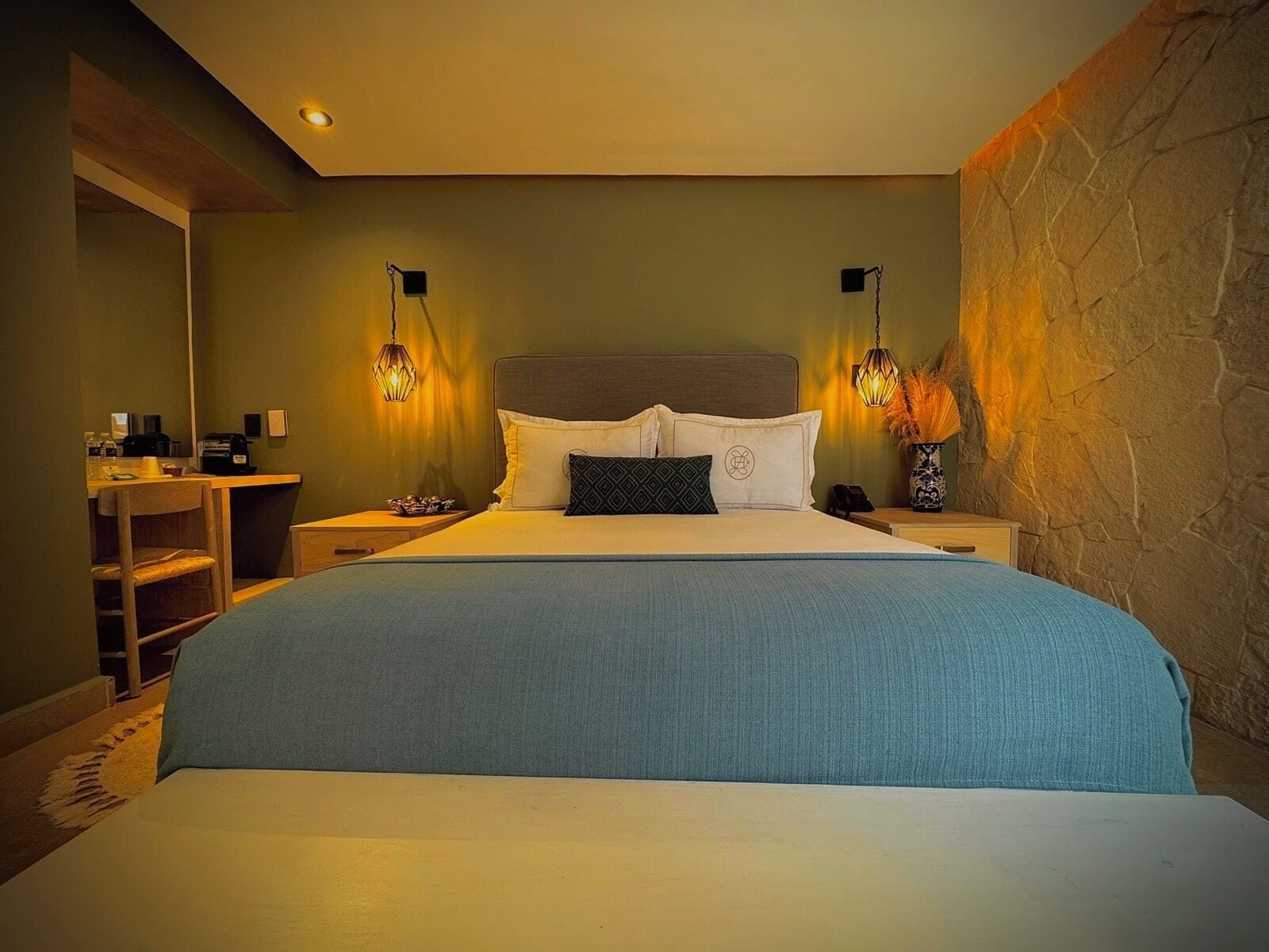 Un dormitorio con una cama grande, mesitas de noche, un escritorio y una silla.