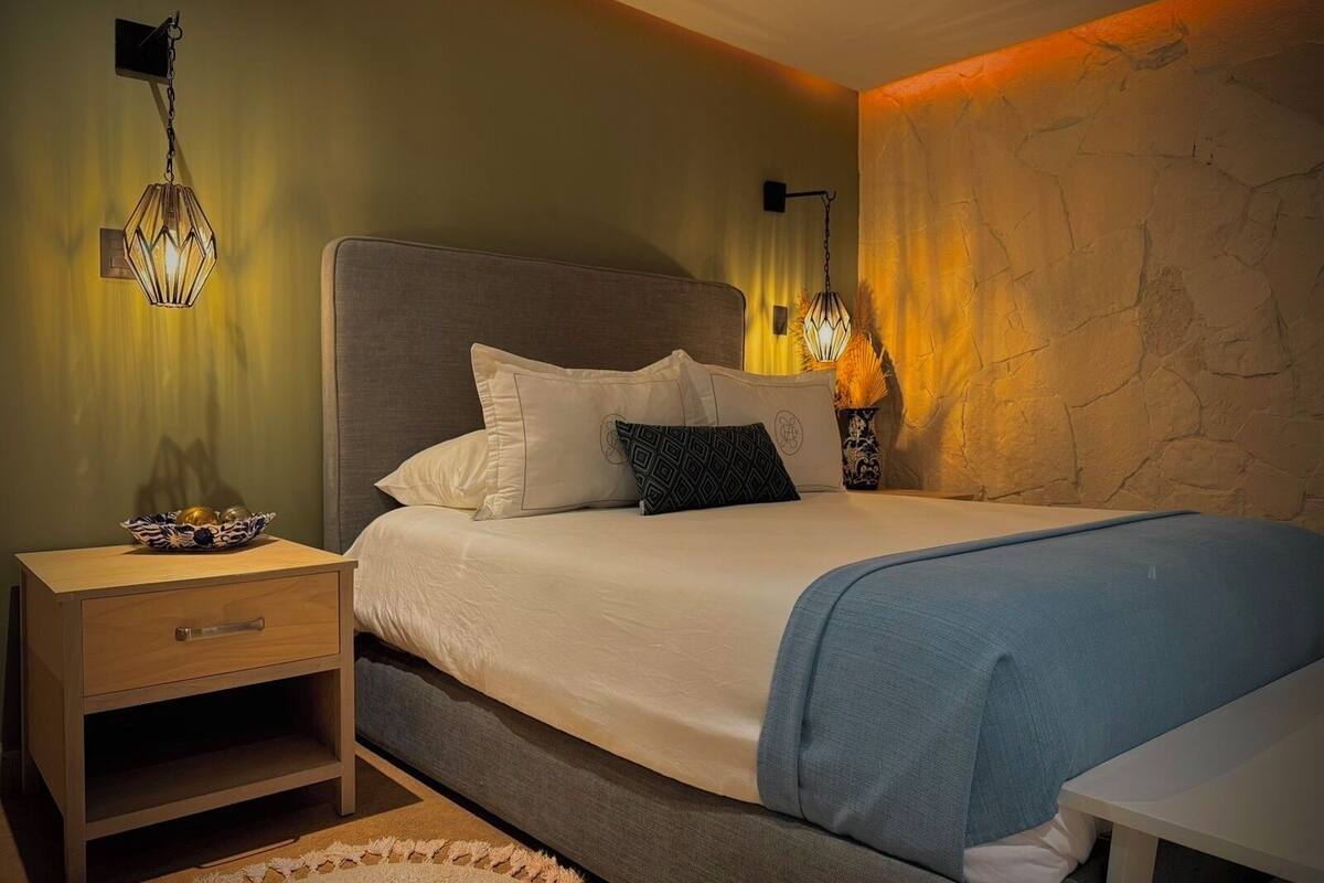 A bedroom with a bed, bedside tables, and wall-mounted lamps.
