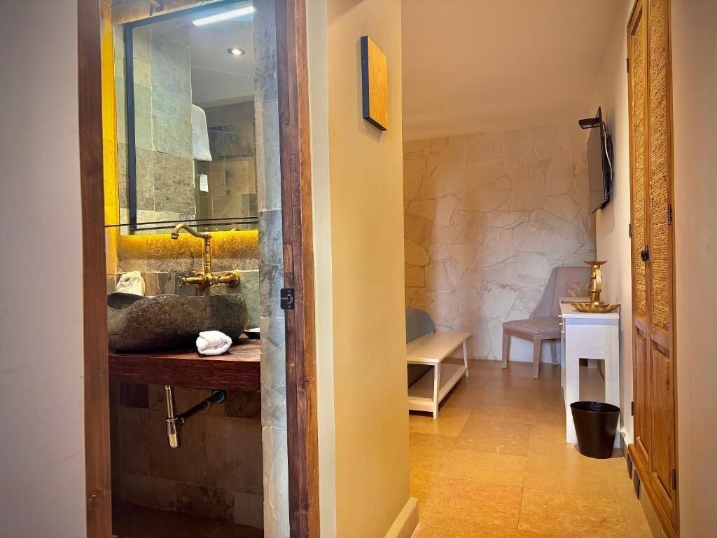 A bathroom with a stone sink, a mirror, and a bench.