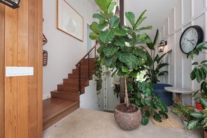 A staircase with wooden steps, a potted plant, a wall clock, and a small table with a patterned top. - Sauna Barn Wellness Retreat on 2 Acres (Princeton)