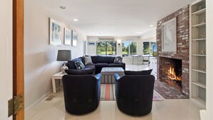 A modern living room with a fireplace, a sofa set, and a dining area with a table and chairs.