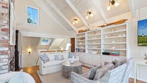 A spacious living area with a high ceiling, white walls, and a built-in shelf with decorative items.