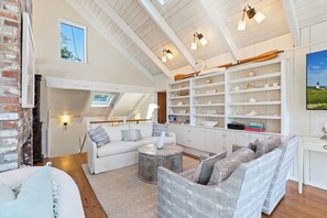 A spacious living area with a high ceiling, white walls, and a built-in shelf with decorative items.