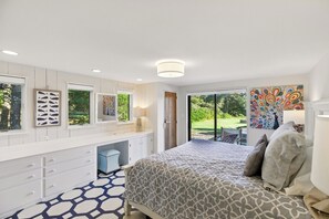 Un dormitorio con cama, cómoda y ventanas amplias.