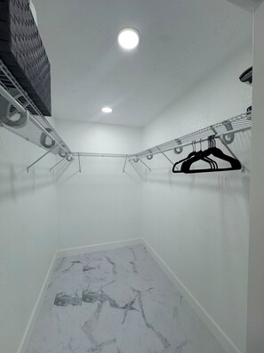 Une pièce avec un luminaire au plafond, un portant à vêtements suspendu et un sol à motifs de marbre.