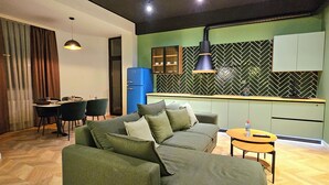 Departamento Deluxe, 2 habitaciones, vista a la ciudad | Área de sala de estar | Smart TV de 90 cm con canales por cable 