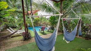 A pool area with two hammocks, a pool, and a covered seating area with chairs. - Cozy 1-bedroom apartment with AC in tranquil Quepos (Quepos)