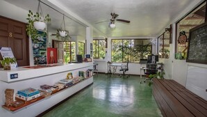 A spacious room with a green floor, a wooden bench, a desk with a computer, and a chalkboard menu. - Cozy 1-bedroom apartment with AC in tranquil Quepos (Quepos)