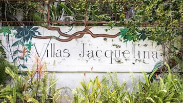 A sign for Villas Jacqueline with a rustic design and lush greenery around it.