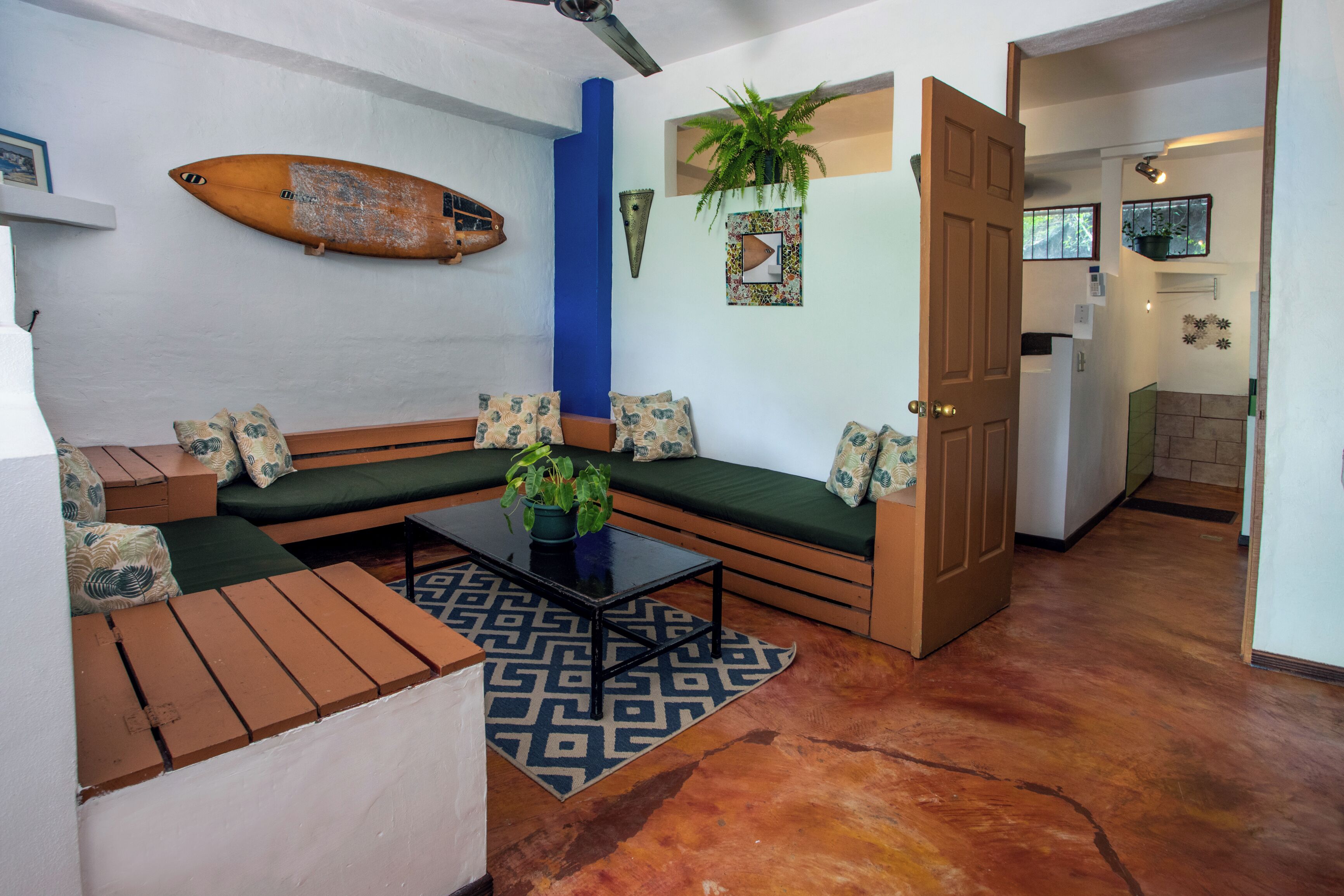 Een woonkamer met een bank, salontafel en een surfplank aan de muur.