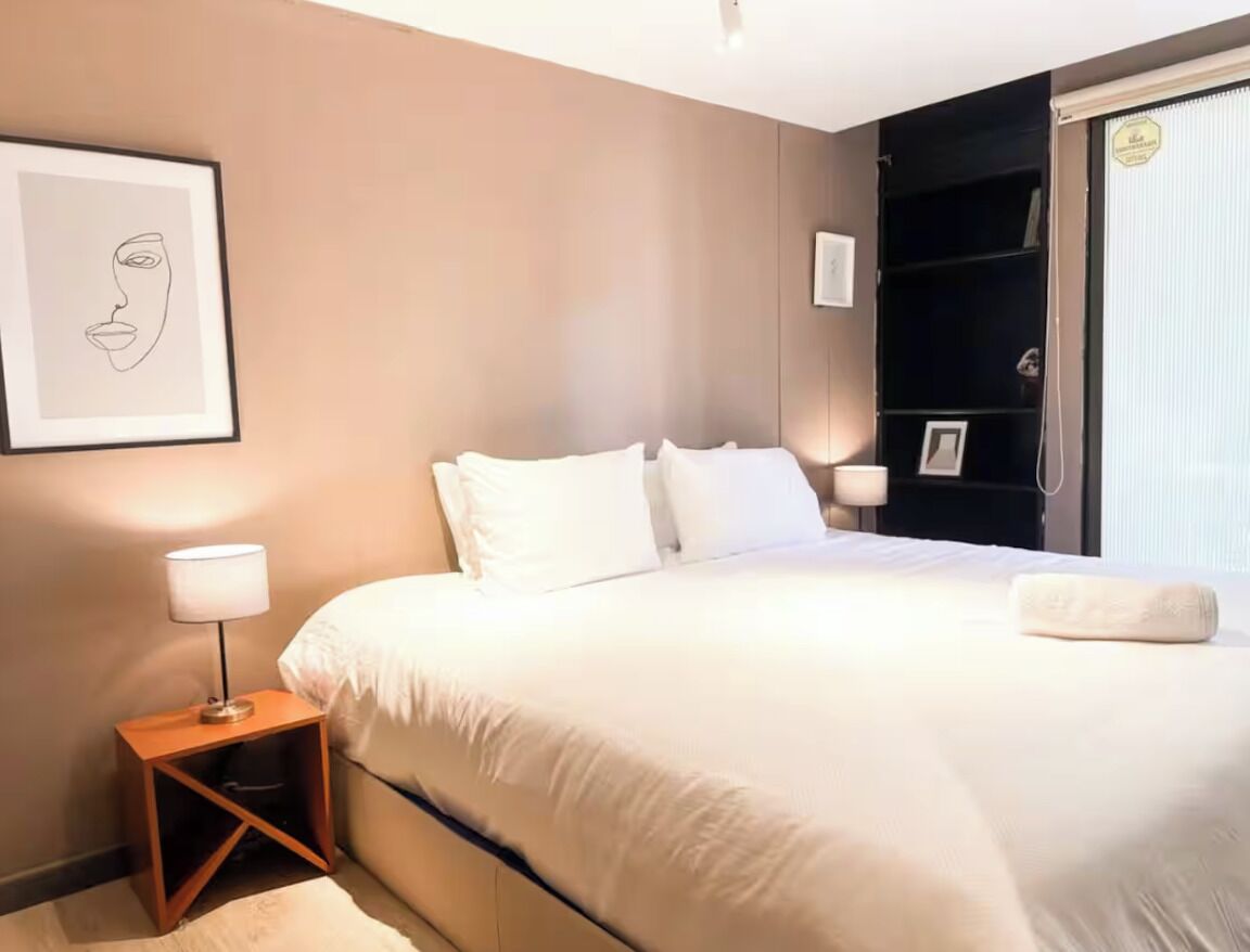 A bedroom with a bed, a nightstand, a framed picture, and a closet.