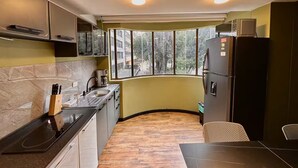 Una cocina compacta con estufa integrada, un lavamanos y un refrigerador. Hay una ventana que ofrece vistas al exterior.
