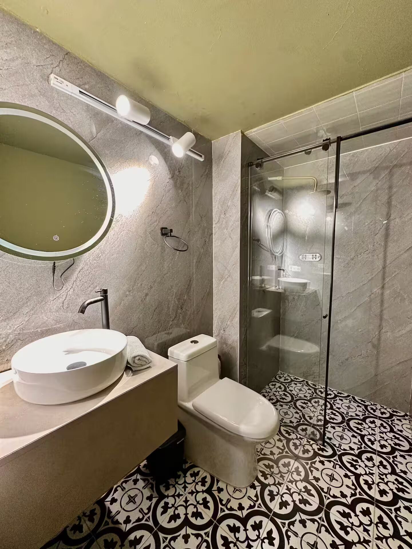 A bathroom with a round sink, toilet, and glass-enclosed shower.
