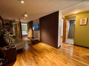 A modern living room with a wooden floor, a sofa, a TV, and a plant. - HF Lujo moderno 3 dormitorios. Parque 93 (Bogotá)