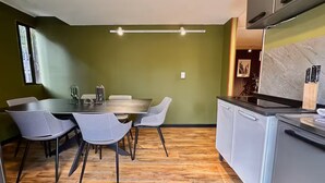 Una cocina moderna con comedor, que presenta piso de madera, una mesa de comedor con sillas y una isla de cocina con pileta y encimera.