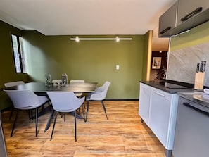 A modern kitchen with a dining area, featuring a wooden floor, a dining table with chairs, and a kitchen island with a sink and countertop. - HF Lujo moderno 3 dormitorios. Parque 93 (Bogotá)