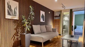 Una sala de estar moderna con un sofá, una mesa de centro, una planta en maceta y suelo de madera.