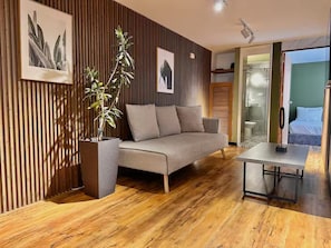 A modern living room with a sofa, a coffee table, a potted plant, and wooden flooring. - HF Lujo moderno 3 dormitorios. Parque 93 (Bogotá)