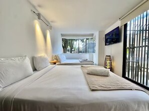 Ein modernes Hotelzimmer mit einem großen Bett, einem Nachttisch, einer Lampe und einem Fenster mit Blick ins Freie.