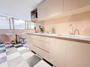 Eine moderne Küche mit Schachbrettboden, einem Essbereich mit Stühlen und einem großen Fenster, das natürliches Licht hereinlässt.