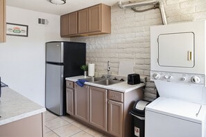 Eine kleine Küche mit Kühlschrank, Herd, Spüle und Schränken.