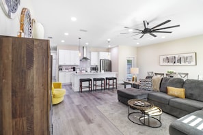 A modern living room with a grey sofa, a coffee table, and a yellow chair. - Heated Pool 3BR home Ybor, close to everything! (Tampa)