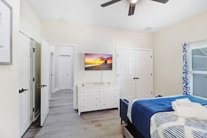 Ein Schlafzimmer mit Bett, Kommode, Gemälde und Deckenventilator.