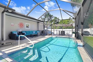 A covered swimming pool with a sun mural, seating area, and a view of the outdoors. - Heated Pool 3BR home Ybor, close to everything! (Tampa)