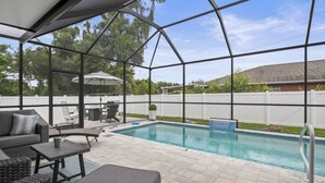 Un espacio al aire libre cubierto con piscina, asientos y vistas al jardín trasero.