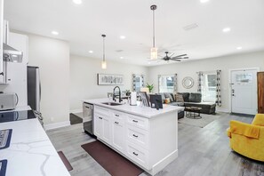 Een moderne keuken met witte kasten, een centraal eiland en een zithoek met een bank en salontafel.